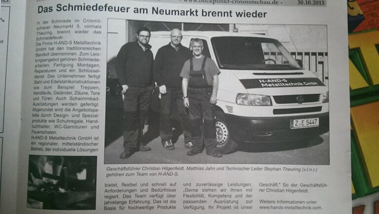 Drei Männer stehen lächelnd vor einem weißen Firmenwagen mit der Aufschrift HANDS Metalltechnik GmbH in einem schwarz-weißen Zeitungsausschnitt mit deutschem Text und einer Schlagzeile über Schmiedearbeiten in Neumarkt.